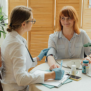 A medical professional examines a woman's arm in a clinical setting.