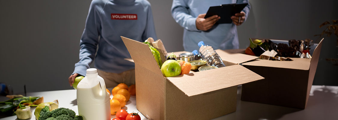 Volunteers packing boxes with food, milk, and canned goods for a community involvement event.